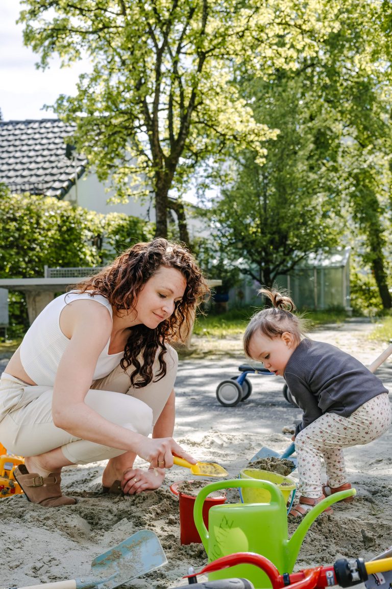 Mutter und Tochter spielen zusammen im Sandkasten